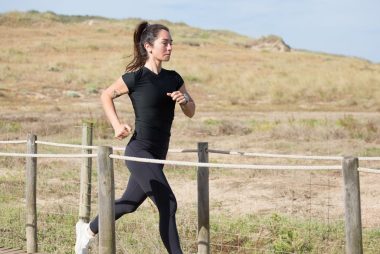 Woman jogging on a sunny day on a wooden path in Portugal, embracing a healthy lifestyle.