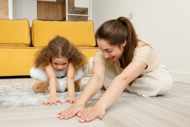 A mother and child practicing yoga exercises together indoors, smiling and bonding.